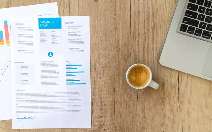 A resume document and a laptop on a desk