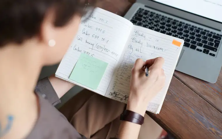 A person taking notes while preparing documents