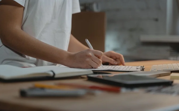 A hand filling out an application on a checklist