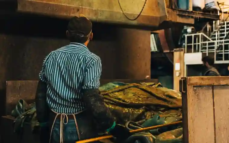 An industrial worker seen from behind, working in a factory