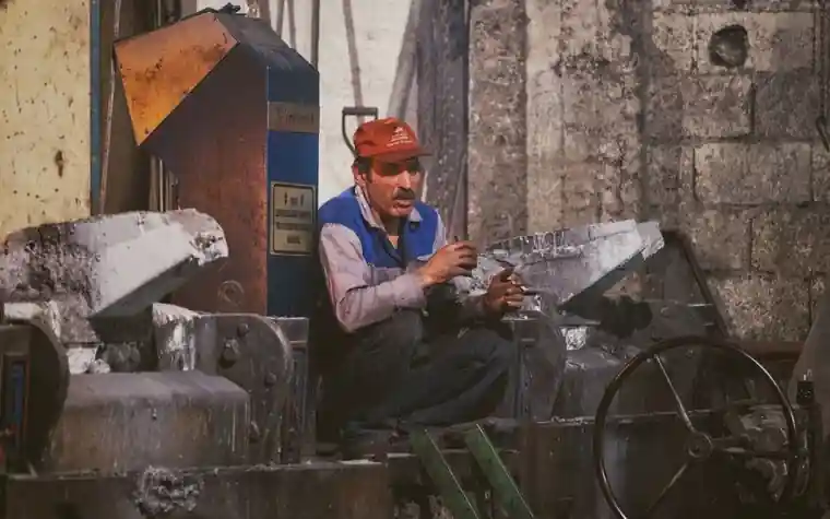 A worker in work clothes sitting and resting during a break at a factory