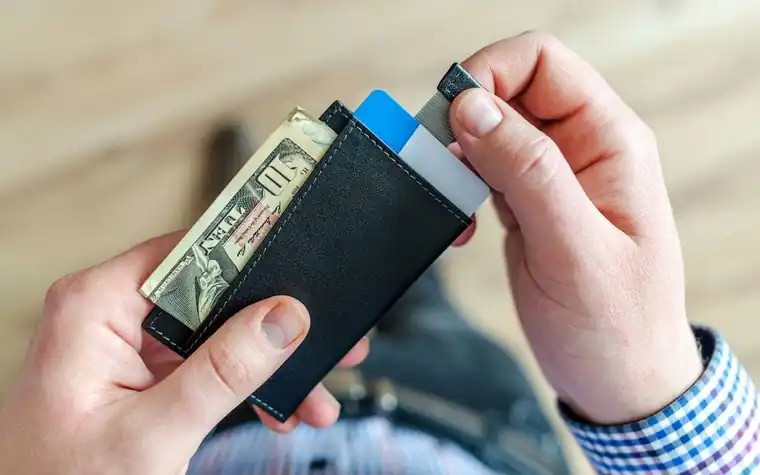 Hands taking a card and banknotes out of a wallet