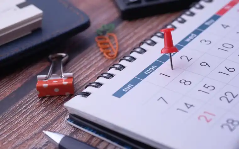 A desk calendar with a pin stuck in a date