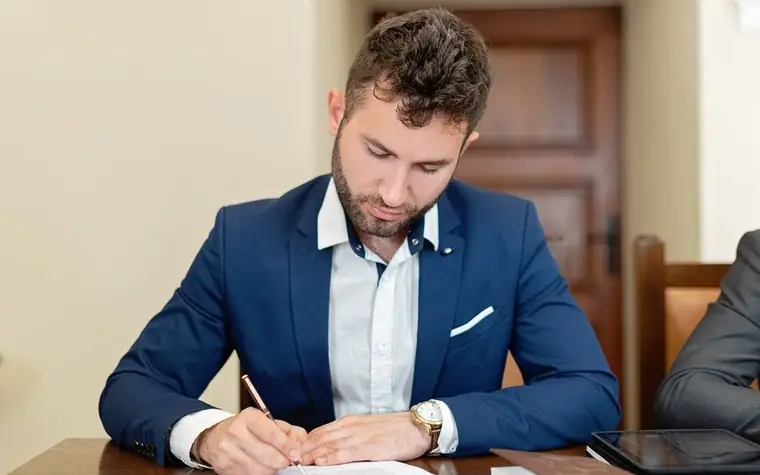 A man signing a document at a desk