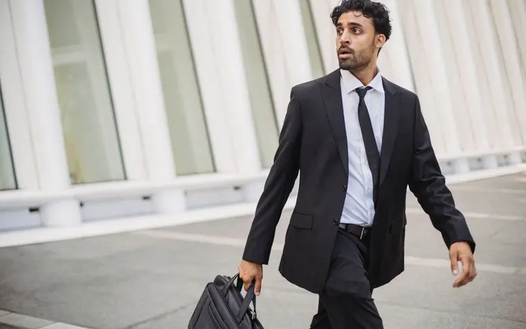 A person walking between city buildings while carrying a briefcase