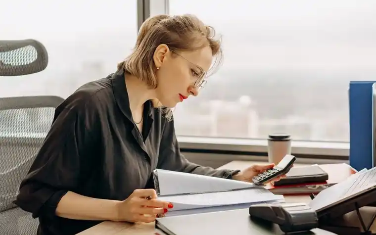 A woman calculating figures with documents and a calculator