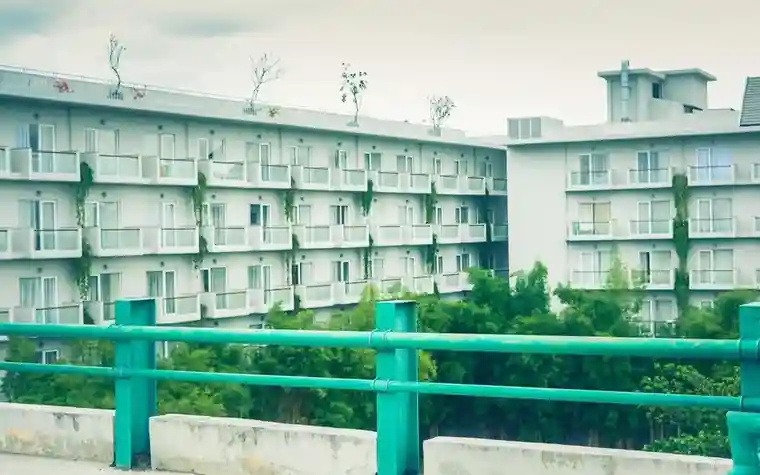 Exterior of a multi-unit residential complex surrounded by a green fence, the kind of housing subject to property tax