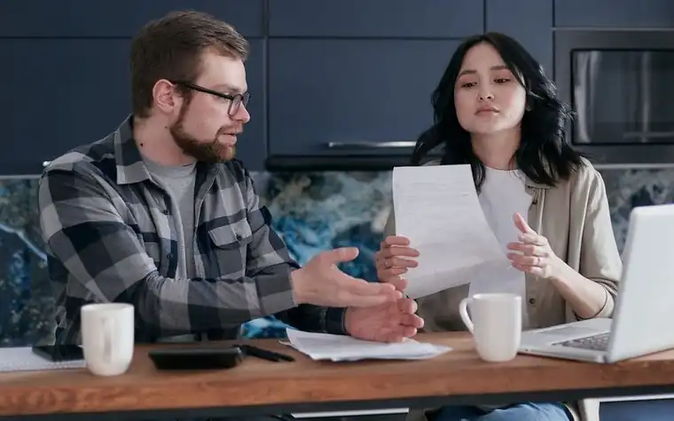 A couple sitting at the dining table talking over a bill together