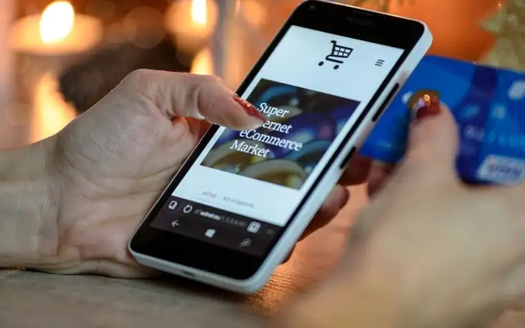 A woman's hand holding a credit card while looking at a phone screen