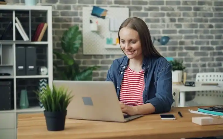 A woman in glasses working in front of a laptop