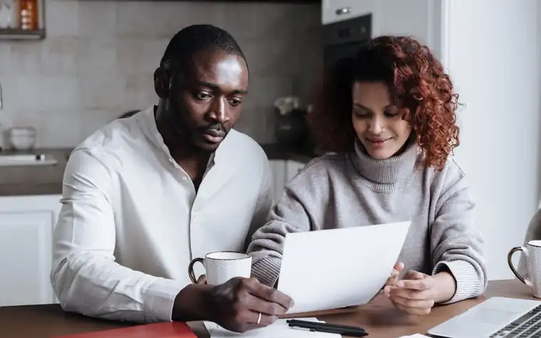 A couple reading documents together at a kitchen table