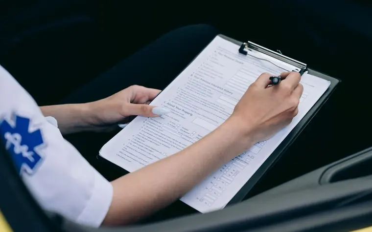 클립보드에 끼운 서식에 펜으로 적는 손