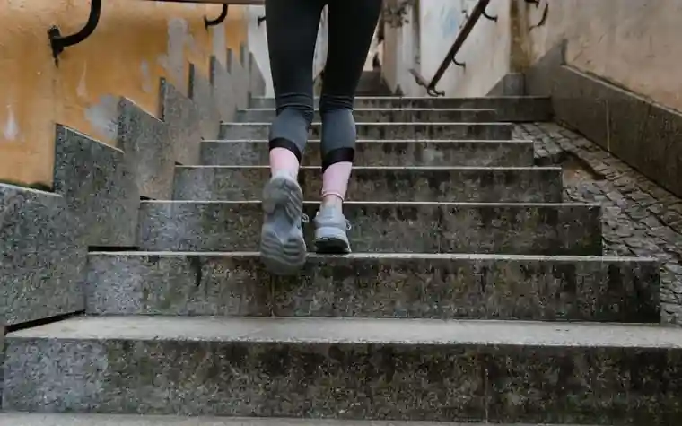 Rear view of a woman climbing outdoor stairs doing weight-bearing exercise