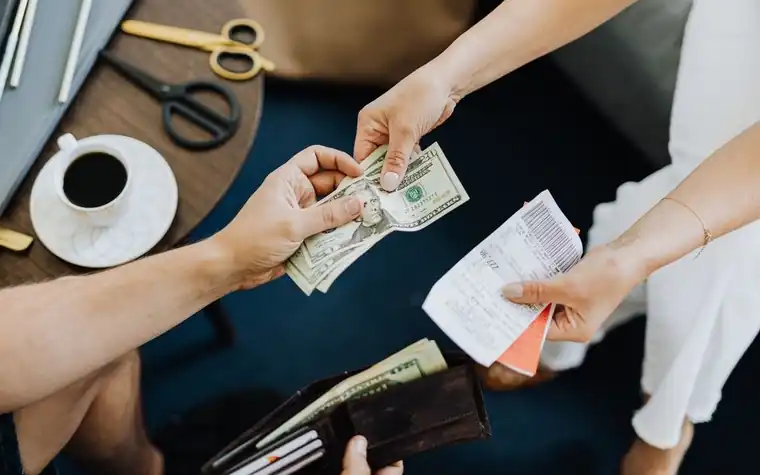 Two people's hands exchanging a receipt and cash