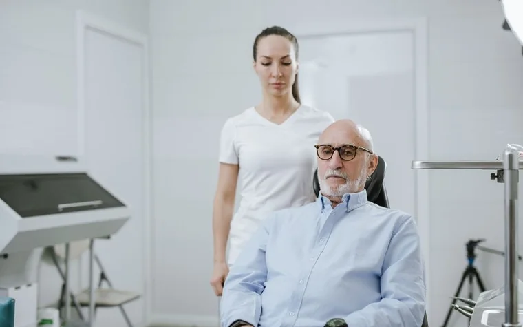 An elderly patient receiving a consultation at a hospital while a caregiver stays close by