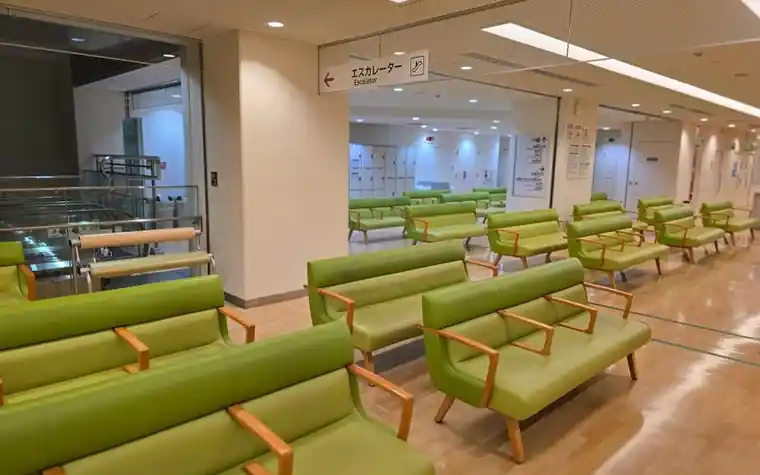 초록색 긴 의자가 줄지어 놓인 병원 대기 공간