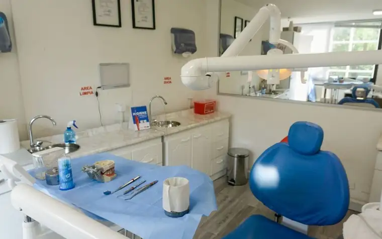 A clean dental examination room with a blue dental chair and equipment