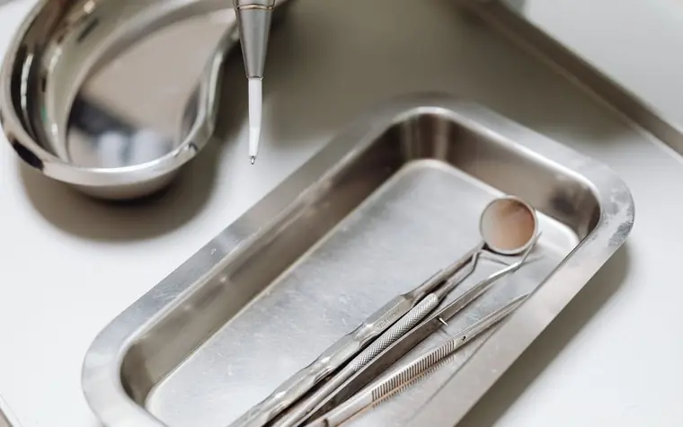 A silver dental tray with a dental mirror and probe