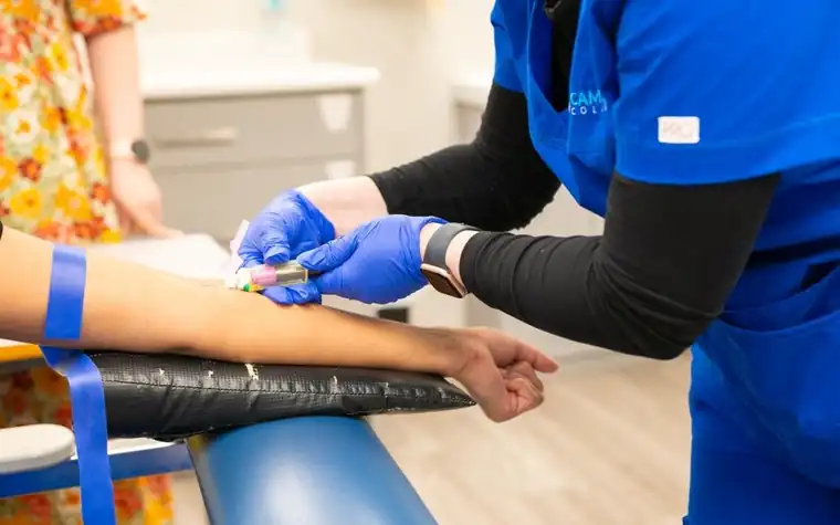 Medical staff in blue gloves drawing blood from an arm