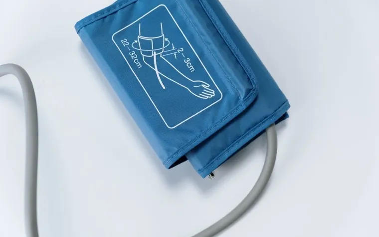 A blue blood pressure cuff and its tube lying on a white surface