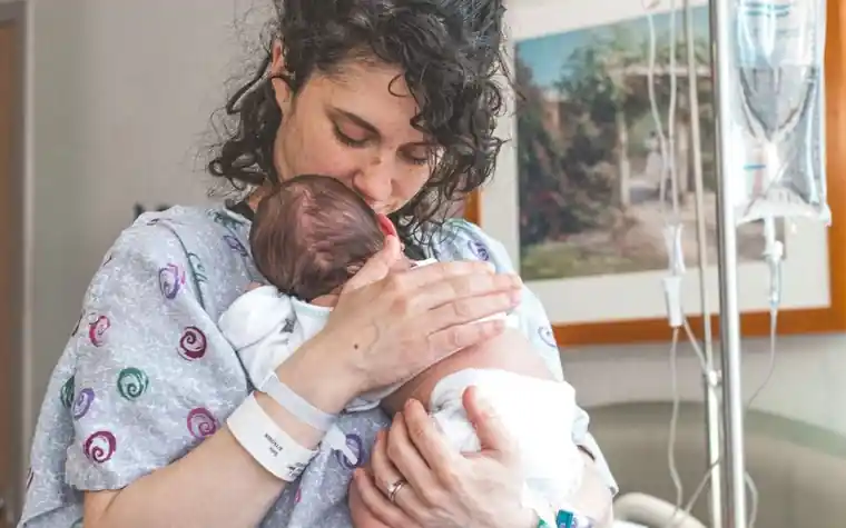 A mother holding a newborn baby on a hospital bed
