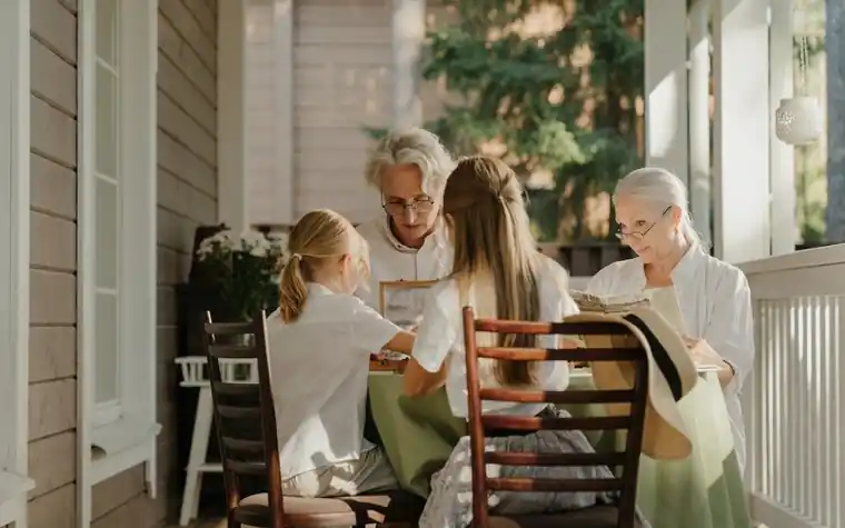 A multigenerational family seated together at a table on a veranda