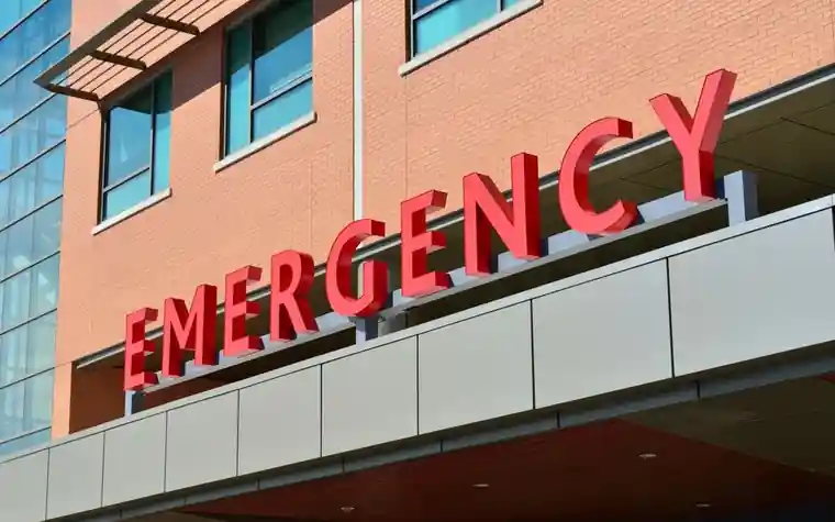 Exterior wall of a hospital emergency building with the word EMERGENCY in red letters