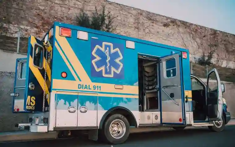 A blue ambulance with its doors open parked at the roadside
