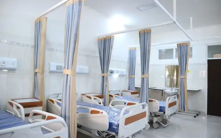 A bright hospital ward with curtains and beds