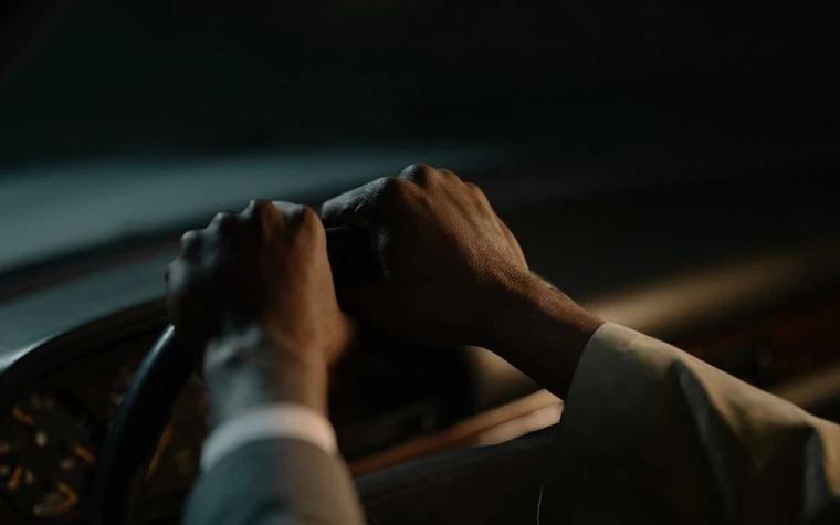 A driver holding the steering wheel with both hands inside a car