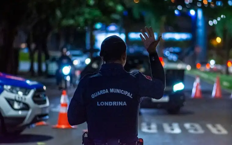 A traffic officer raising a hand to guide vehicles on a night road