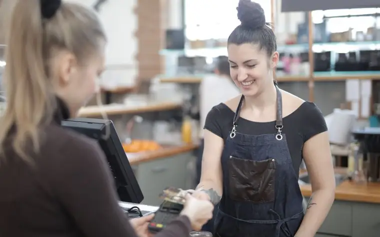 A cafe cashier helping a customer with a card payment at the counter