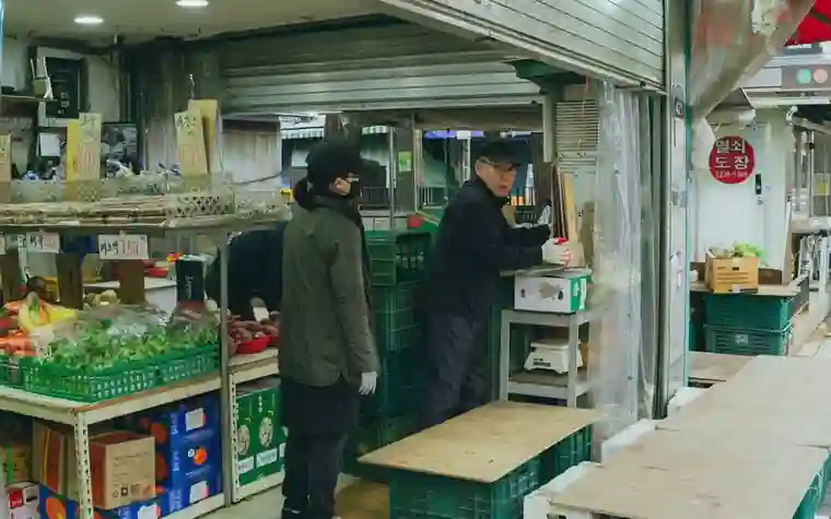 A vendor and a customer talking in front of a shop in a market alley