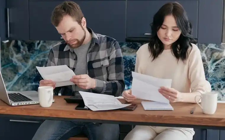 A couple at a dining table going over receipts and documents side by side