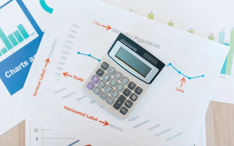A calculator and budget documents resting on printed graphs