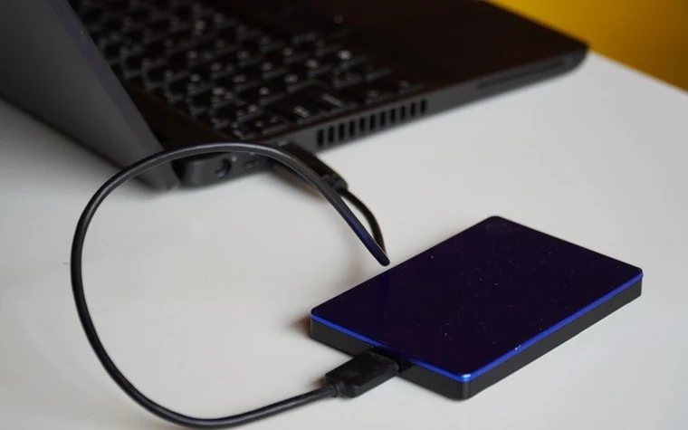 An external hard drive connected to a laptop by cable