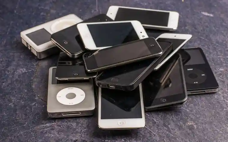 A pile of old iPods and smartphones stacked together