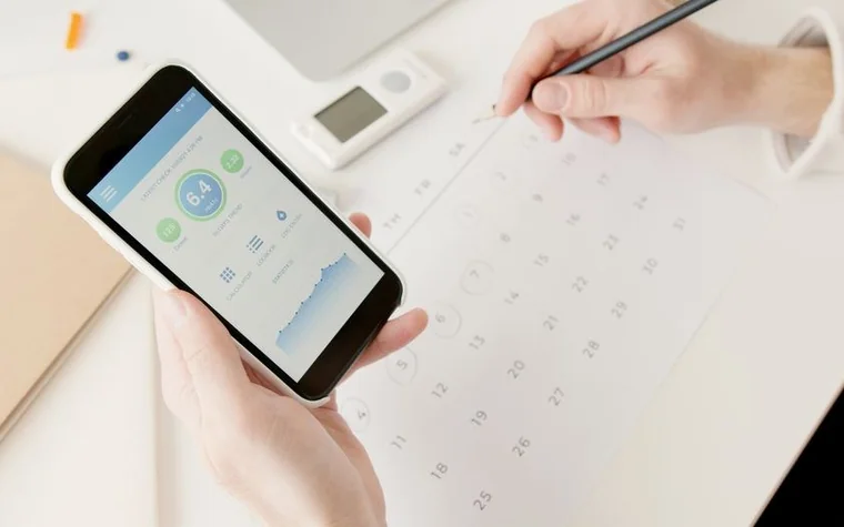 A hand holding a smartphone showing a data usage screen beside a calendar