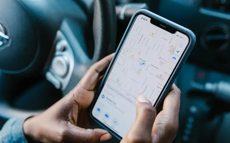 A person holding a smartphone with a map screen displayed