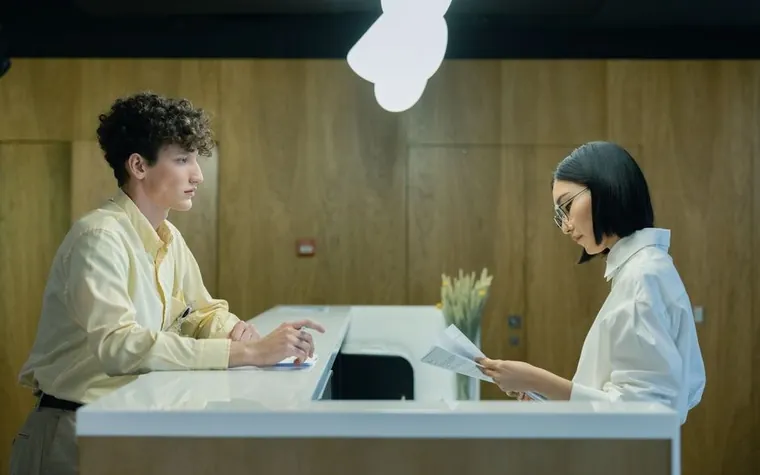 A staff member and a visitor reviewing documents at an information desk