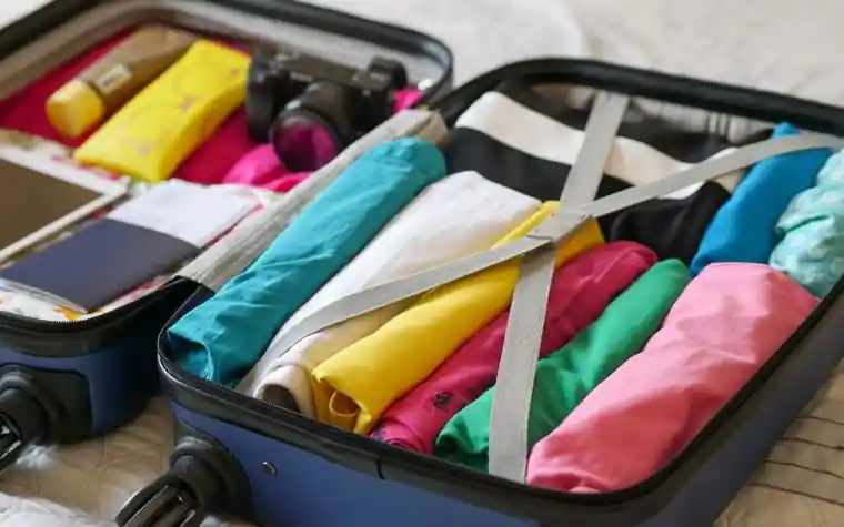 An open suitcase packed with a passport, camera and clothes