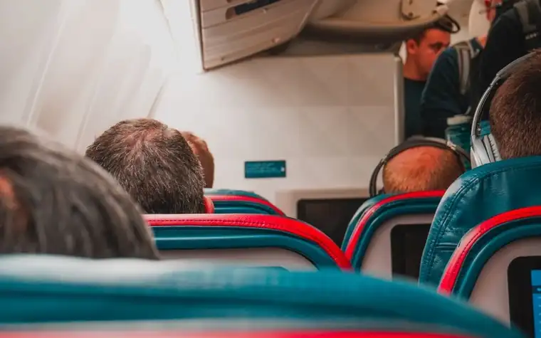 The backs of passengers seated in an airplane cabin